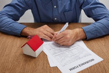 木桌上的人簽保險(xiǎn)表與房屋模型的裁剪