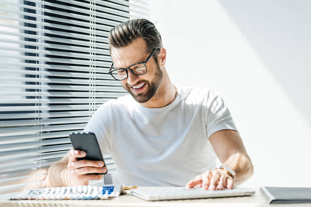 微笑的人使用智能手机, 而坐在工作场 微笑的人使用智能手机, 而坐在工作场