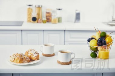 廚房白色桌面上的早餐杯咖啡和牛角面包的特寫視圖