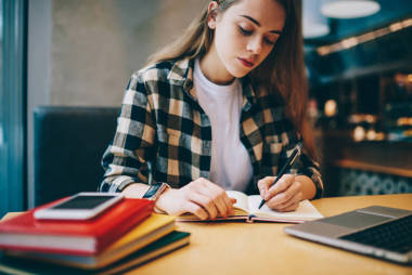 認真的女性自由職業(yè)者花時間在大學圖書館, 而規(guī)劃的工作過程在教科書, 有吸引力的集中婦女寫審查訪問自助餐廳在室內(nèi)筆記本