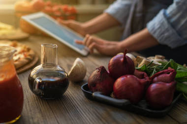 在廚房的平板電腦上尋找食譜的年輕女子。健康食品。健康的生活方式。在家做飯。根據(jù)片劑屏幕上的食譜烹調(diào)。技術(shù)理念。色調(diào)圖像