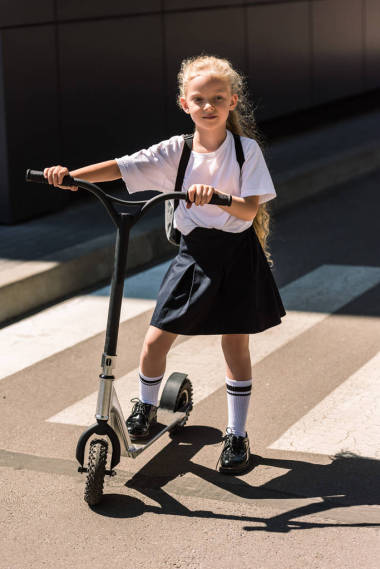 全長視圖的可愛的小女生背包騎摩托車在街上