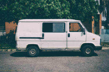 老白貨車速遞車停在一堵墻前, 樹的背景。沒有人