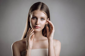 一个美丽的年轻女孩的肖像与裸体化妆在工作室灰色背景