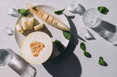 用薄荷和冰塊在白色玻璃上放瓜片和清爽飲料的頂級視圖