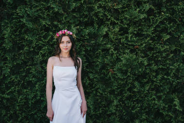 漂亮的新娘擺在傳統的白色婚紗禮服和花花圈