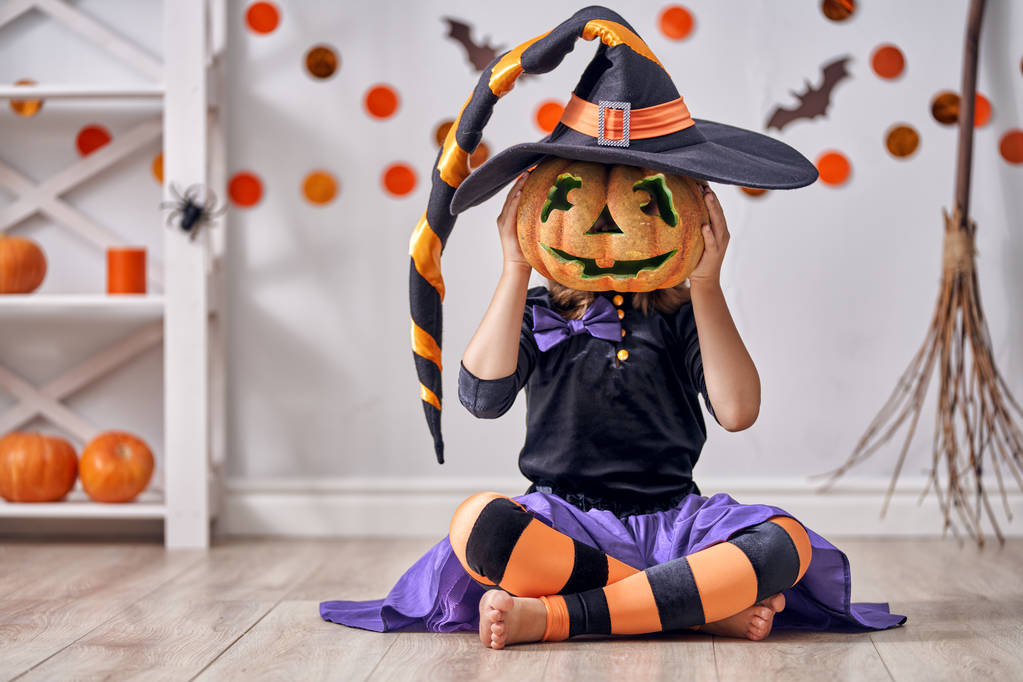 万圣节快乐!可爱的小笑的女孩在巫婆服装与南瓜 万圣节快乐!可爱的小笑的女孩在巫婆服装与南瓜