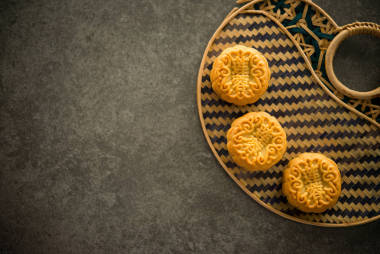 中秋節(jié)期間，人們會(huì)用傳統(tǒng)的月餅招待親朋好友。平臺(tái)頂視圖昏暗的燈光與復(fù)制空間。月餅上的漢字在英語中代表“蓮蓉”