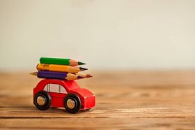 微型红色汽车携带彩色铅笔在木桌上。返回学校概念