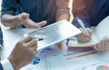 Businessteam 正在分析圖。他們用平板電腦和秘書做筆記