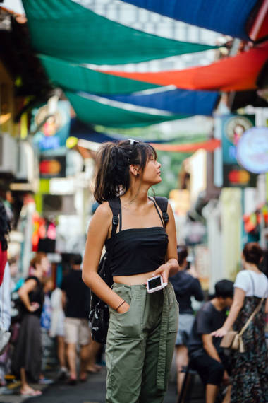 年輕的亞洲婦女在休閑服裝使用智能手機 