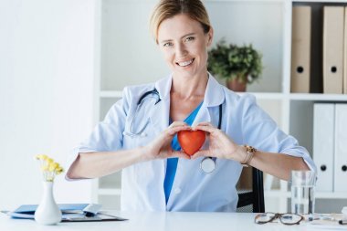 快樂女醫(yī)生白大衣顯示心臟符號在辦公室表