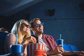 欢快的情侣在3d 眼镜与爆米花一起看电影在电影院