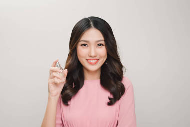 女孩用香水，年輕美麗的女人控股瓶香水和嗅到香氣，色調(diào)柔和的米色和加噪聲