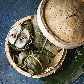 亚洲大米 piramidal 从大米木薯粉中蒸饺子, 香蕉叶中的肉馅在竹蒸笼上, 上面有蓝色的纹理背景。顶部视图, 空间。方形图像