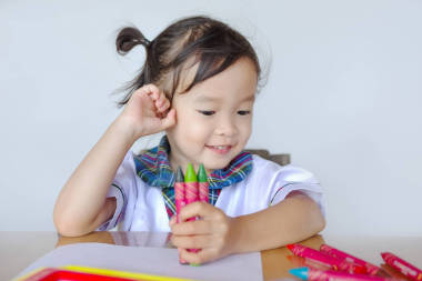 快樂可愛的亞洲小朋友坐在桌邊玩五顏六色的玩具
