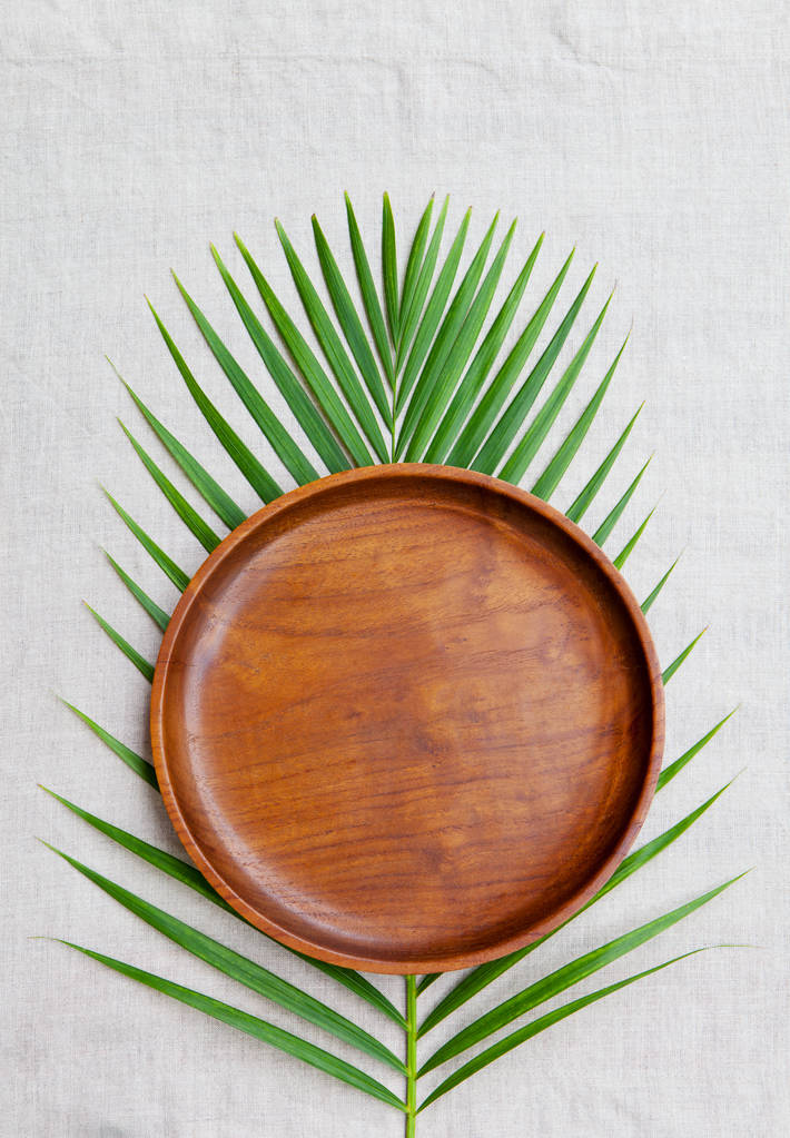 用棕榈叶天然亚麻纺织背景上的木板。复制空间。顶视图