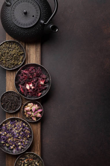 各種干茶品種。黑色, 綠色和草藥茶在碗上的木制邊框。具有復(fù)制空間的頂部視圖