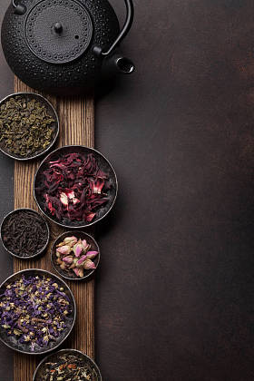 各种干茶品种。黑色, 绿色和草药茶在碗上的木制边框。具有复制空间的顶部视图