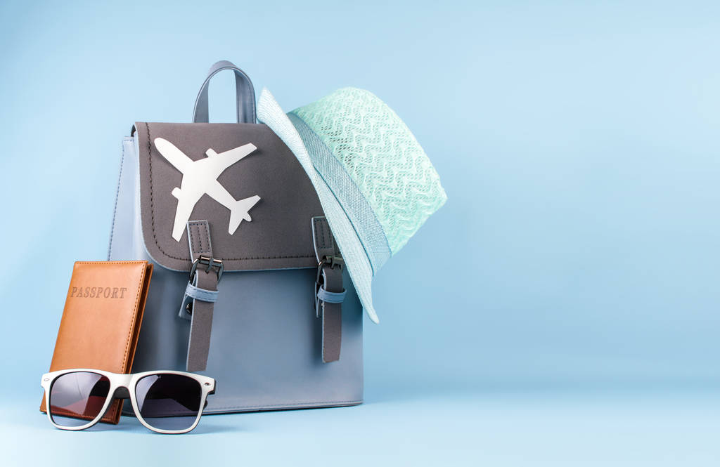 女性时尚旅游背包带护照和帽子在蓝色背景下 女性时尚旅游背包带护照和帽子在蓝色背景下