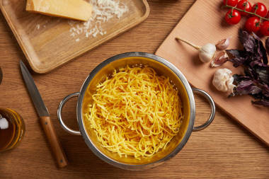 煮熟的意大利面在金屬漏勺周圍的配料為面食在木桌上