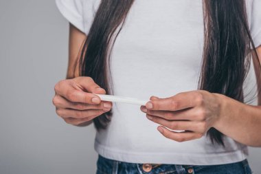 年輕的黑發(fā)婦女舉行妊娠試驗(yàn)隔離灰色的拍攝