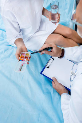 老年男性醫(yī)生用聽診器指著醫(yī)院病房女性病人的圖像