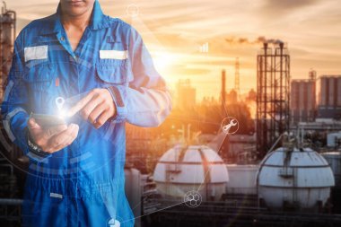 亞洲工程師站在石油天然氣精煉廠背景上手持智能手機, 工程師規(guī)劃工作理念, 石化工業(yè)廠房專業(yè)技師監(jiān)控