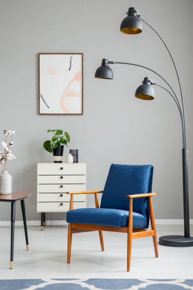 黑燈旁邊的藍(lán)色木扶手椅在灰色公寓內(nèi)部與海報(bào)和植物。真實(shí)照片