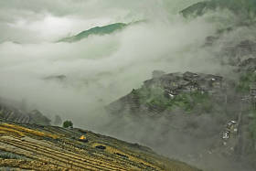 神秘的山丘和村庄在雾中。有薄雾的秋天风景与米梯田。中国, 阳朔, 龙胜