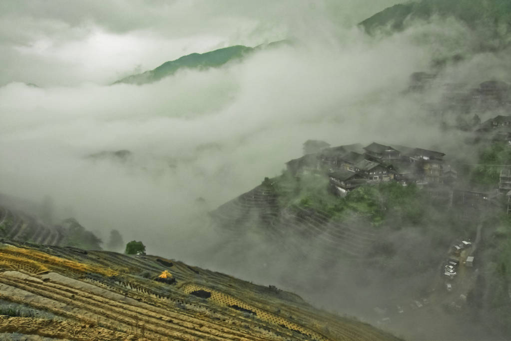 神秘的山丘和村庄在雾中。有薄雾的秋天风景与米梯田。中国, 阳朔, 龙胜