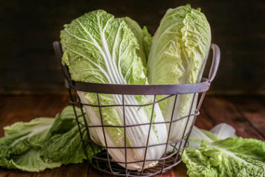 木桌上有新鮮熟卷心菜的金屬籃