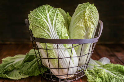 木桌上有新鮮熟卷心菜的金屬籃