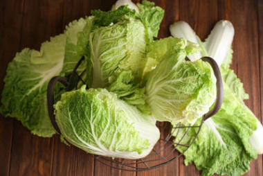 木桌上有新鮮熟卷心菜的金屬籃