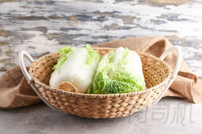 灰色桌上有新鮮熟卷心菜的柳條籃