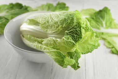 新鮮熟卷心菜碗在輕的木桌上圖片