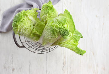 新鮮熟白菜金屬籃在輕木桌上照片