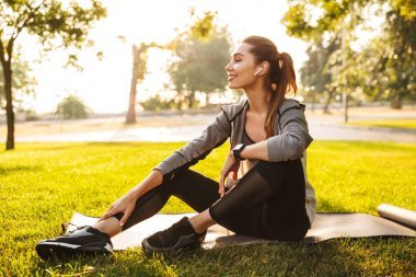 圖片的美麗可愛健身運動婦女在公園戶外聽音樂與耳機?？匆贿?