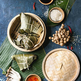 亚洲大米 piramidal 从大米木薯粉中配以竹蒸笼为食的香蕉叶制成的包子。配料, 调味汁。蓝色纹理背景。顶部视图。方形图像