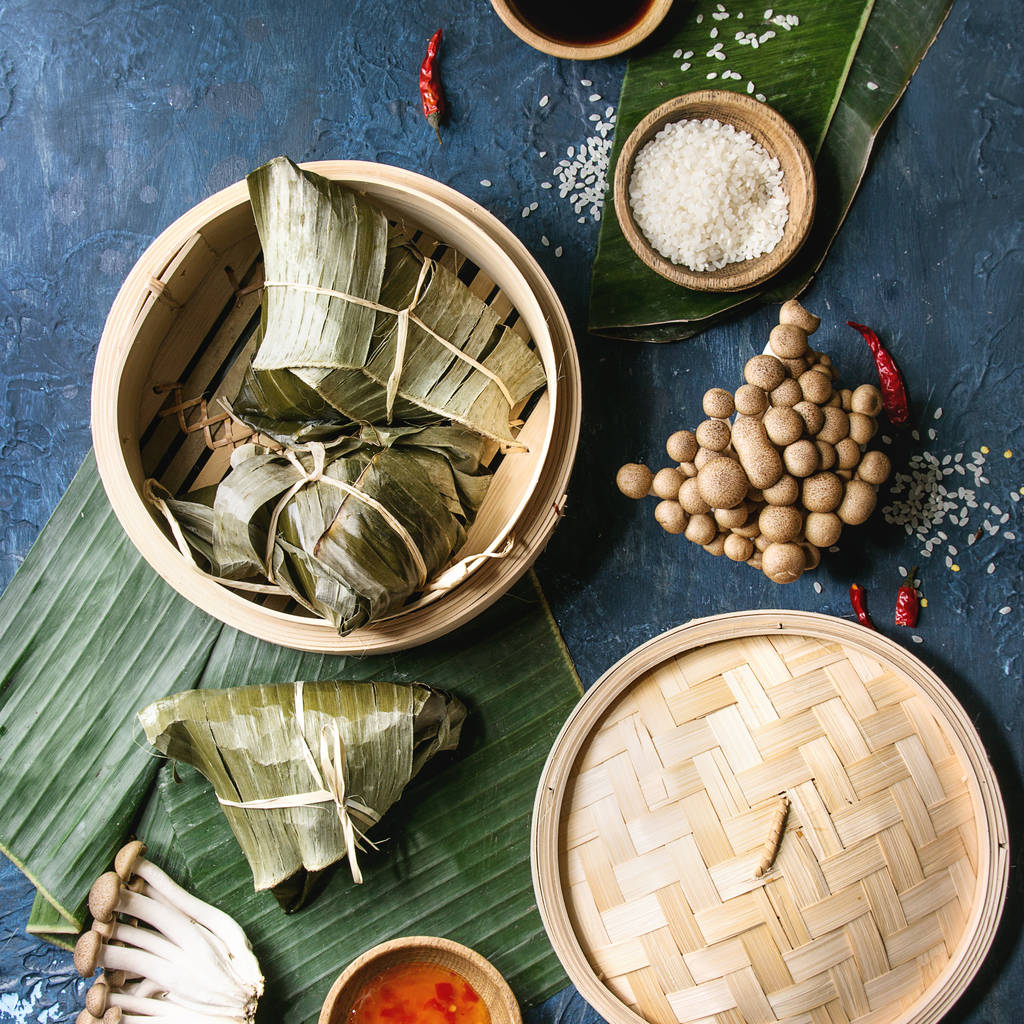 亚洲大米 piramidal 从大米木薯粉中配以竹蒸笼为食的香蕉叶制成的包子。配料, 调味汁。蓝色纹理背景。顶部视图。方形图像