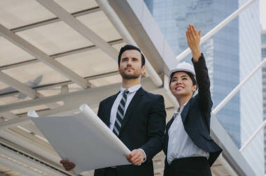 集團的企業(yè)或工程師的婦女和男子與安全頭盔和藍圖規(guī)劃在建設和檢查他們的工作在現(xiàn)代城市, 規(guī)劃啟動新項目, 成功的概念