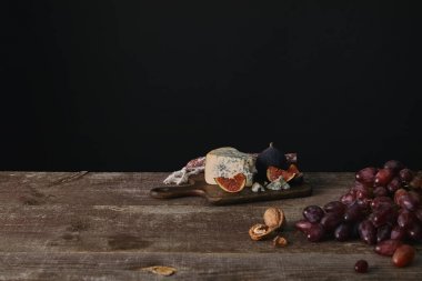 新鮮成熟的葡萄, 堅果和美味的奶酪在木桌上的黑色