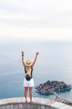 后視圖的婦女站在舉手和看在圣史蒂芬島在亞得里亞海, 布德瓦, 黑山
