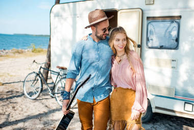 嬉皮女孩和人擁抱和步行與吉他在拖車附近