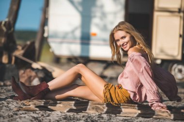 迷人的嬉皮女孩躺在毯子附近的露营车