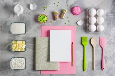 烹飪烘焙為孩子平躺的背景概念。粉紅色綠紙白色筆記本廚房