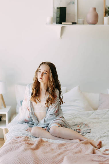 女孩在清晨的床上和浴衣, 醒來, 并準(zhǔn)備工作。生產(chǎn)日。微笑和歡笑。躺在床上, 趕上日出。在臥室里快樂的早晨