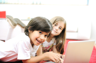 小小的女孩和男孩躺著筆記本在家里地上