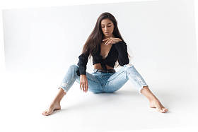 穿着黑色衬衫和白色背景的蓝色香蕉牛仔裤的年轻酷嬉皮士女孩。时尚的现代风