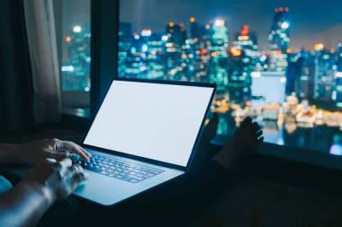 婦女自由職業(yè)者的工作是使用筆記本電腦在家庭辦公室晚上。從窗口鳥瞰城市天際線。自由生活